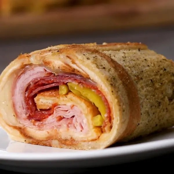 Sliced Stromboli filled with ham, cheese, and peppers on a plate