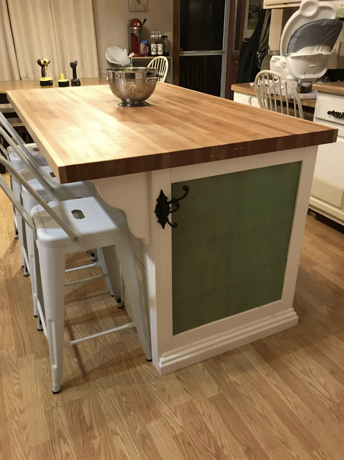 Kitchen island with a butcher block top and white stools, equipped with shelves and storage space