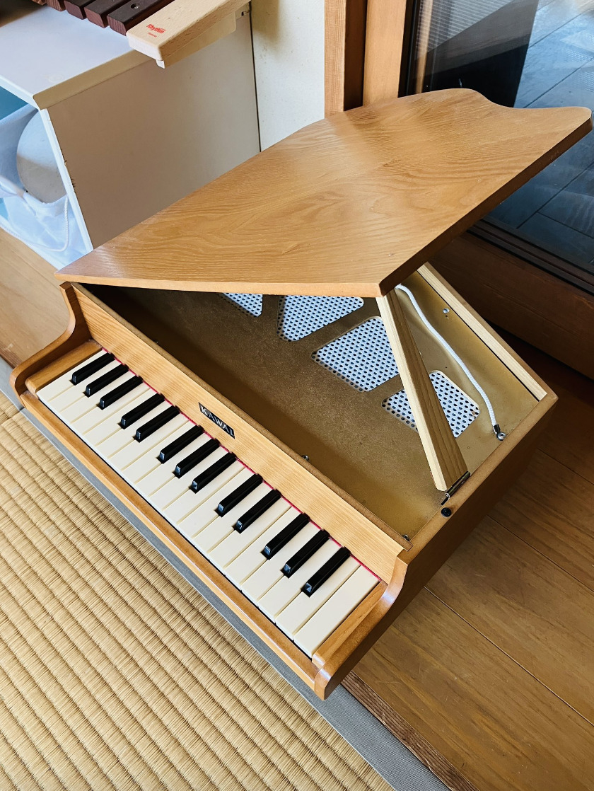木製のおもちゃのピアノが床に置いてあります。