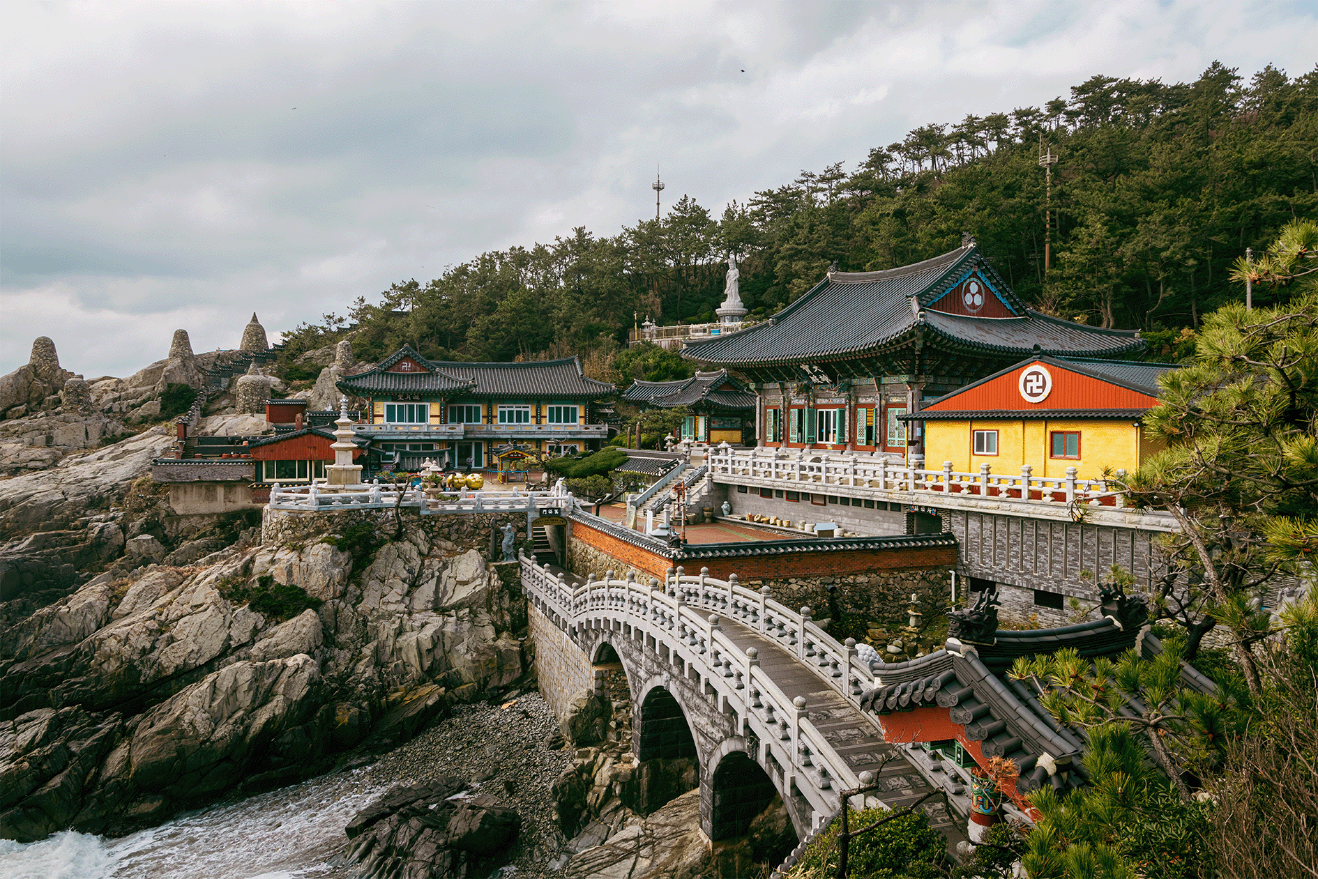 Traditional temple by the sea with connecting arched bridges and rocky landscape