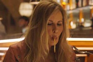Woman eating spaghetti in a restaurant setting