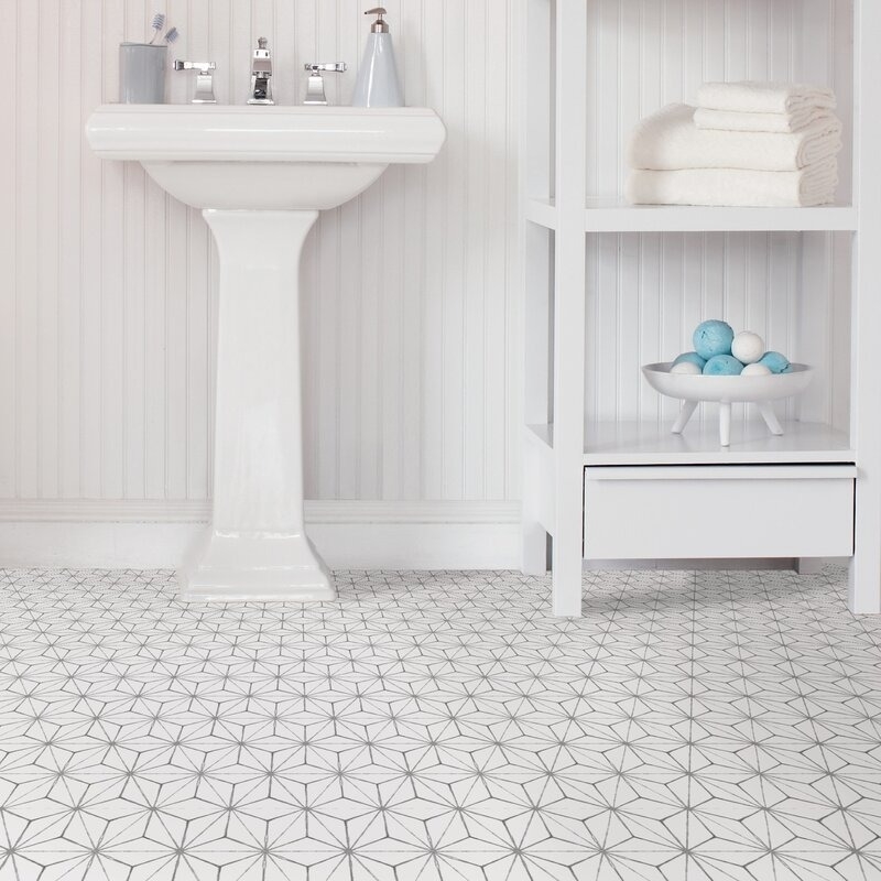 Bathroom with a pedestal sink, shelving unit with towels, and geometric patterned floor