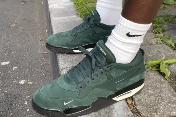 Person wearing green Nike Air Max sneakers standing on pavement
