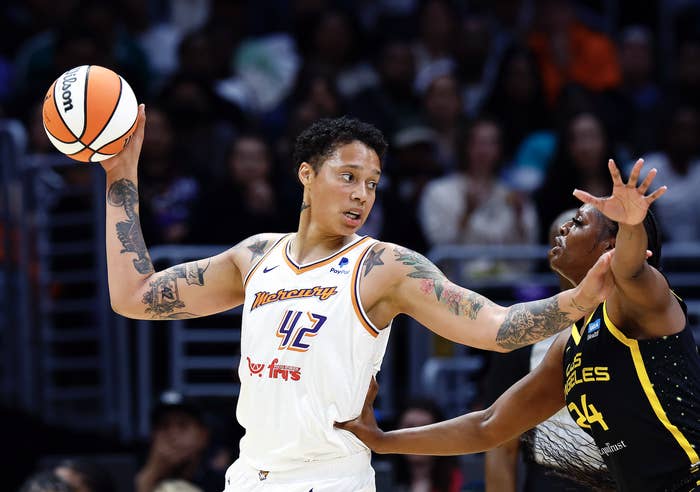 Basketball player in white jersey holding ball while defending against player in dark jersey