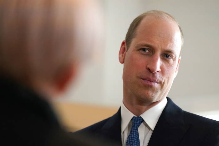 Prince William in a blue suit engages in conversation