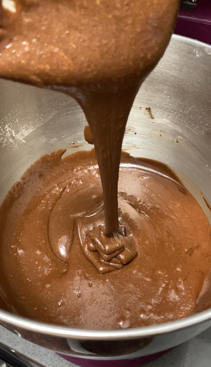 A bowl of chocolate brownie batter being poured