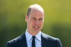 Prince William in a suit smiling outdoors, relevant to a current news article