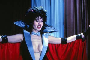Geena Davis in vampire costume with cape and fangs
