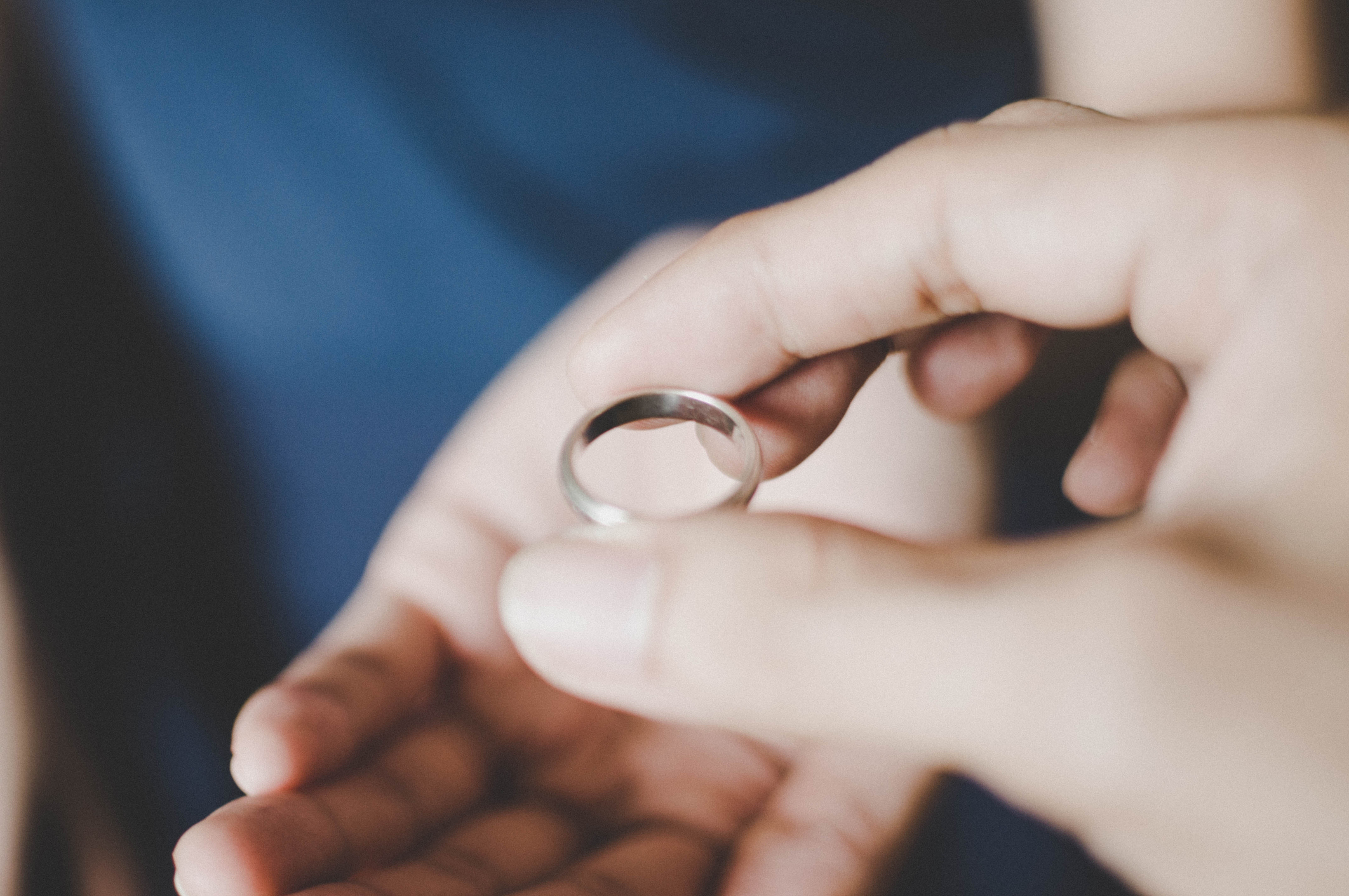 Close-up of a hand holding a silver ring, about to hand it to someone else