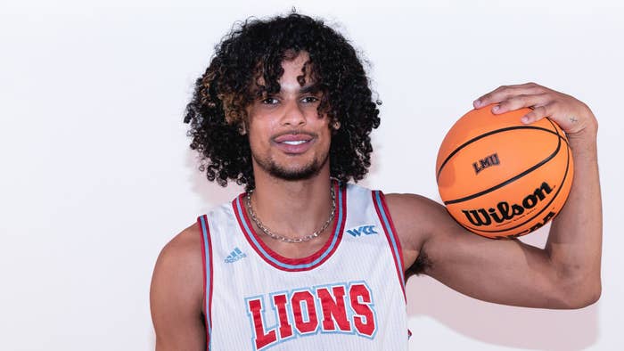 Smiling basketball player holding a ball, wearing a &#x27;LIONS&#x27; jersey