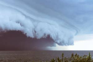 Impressive shelf cloud over a body of water with a visible horizon line