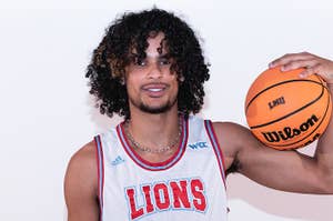 Smiling basketball player holding a ball, wearing a 'LIONS' jersey