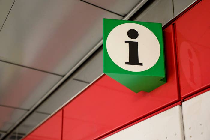 Information sign with a white letter &#x27;i&#x27; on a green background, mounted on a red and grey wall