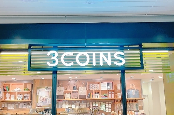 3COINSの店舗入口、棚に様々な商品、店内にいる顧客たち。