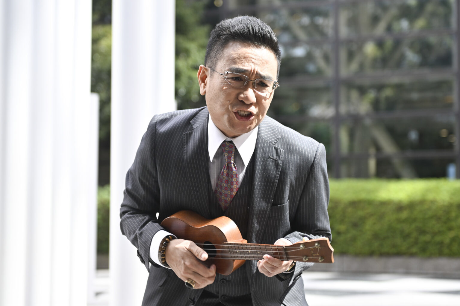 スーツを着た男性がウクレレを弾いている