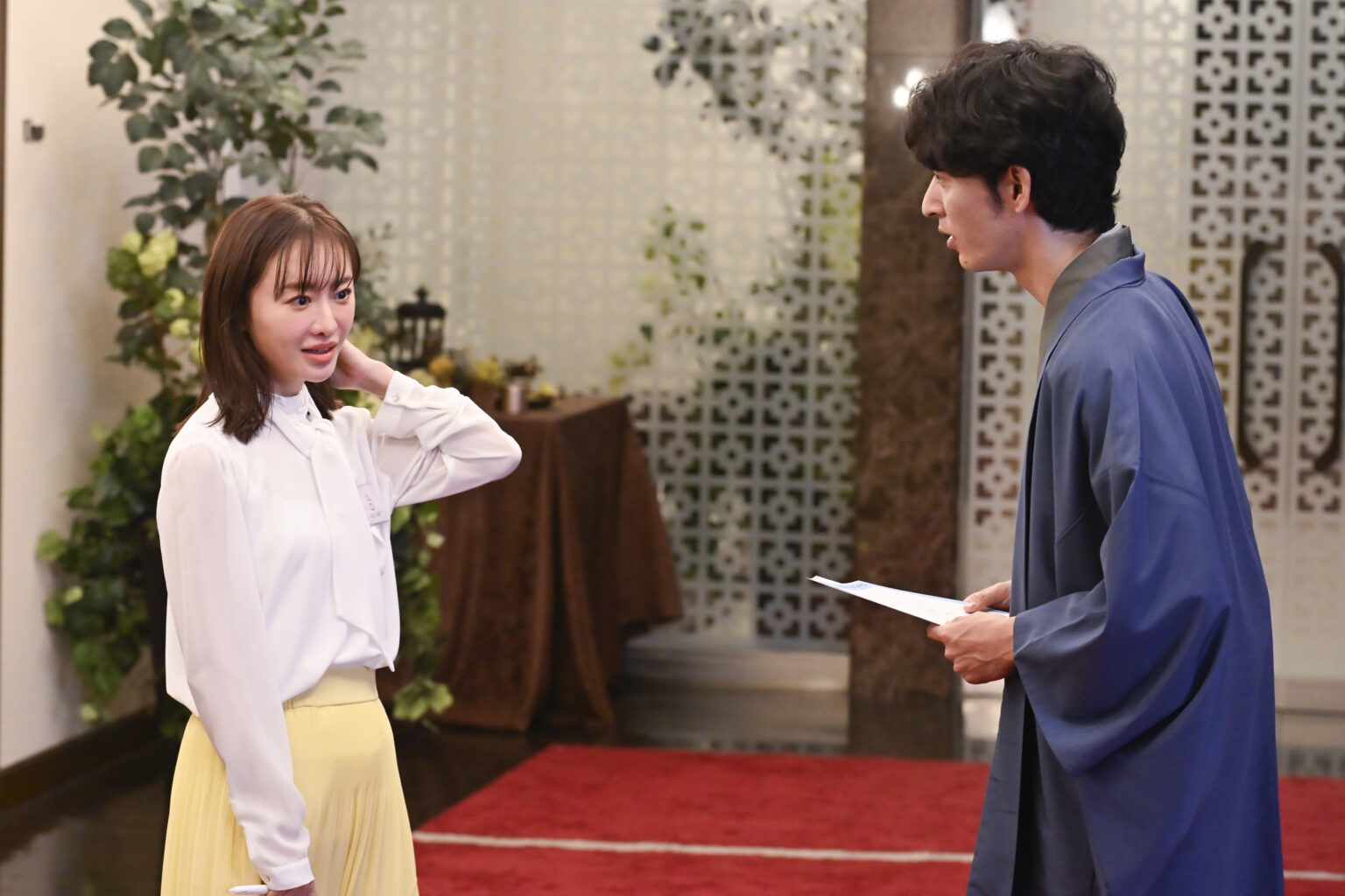 二人の俳優がセットで対話をしているシーン。