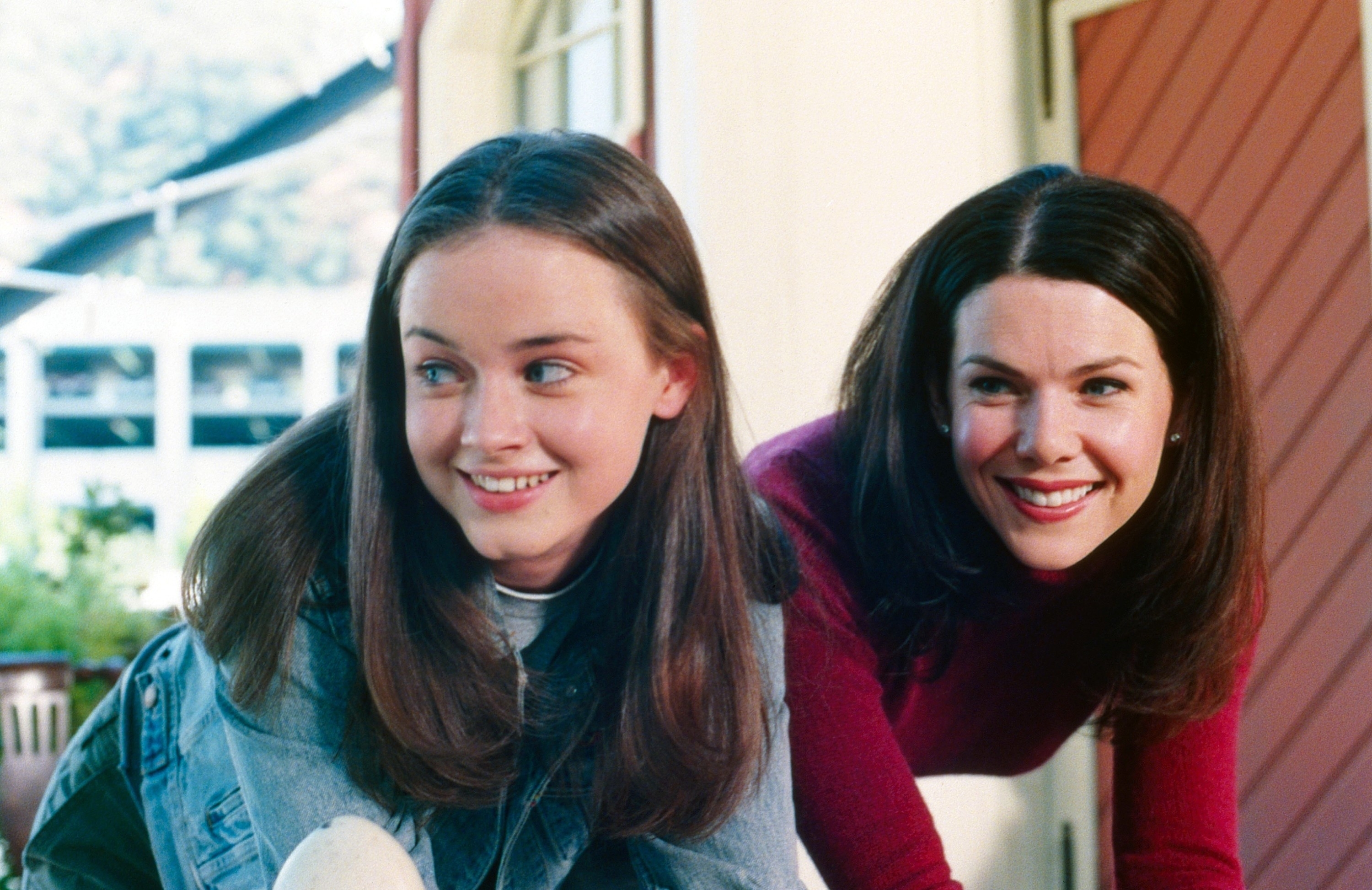 Rory and Lorelai from &quot;Gilmore Girls&quot; lean forward, smiling, in casual attire