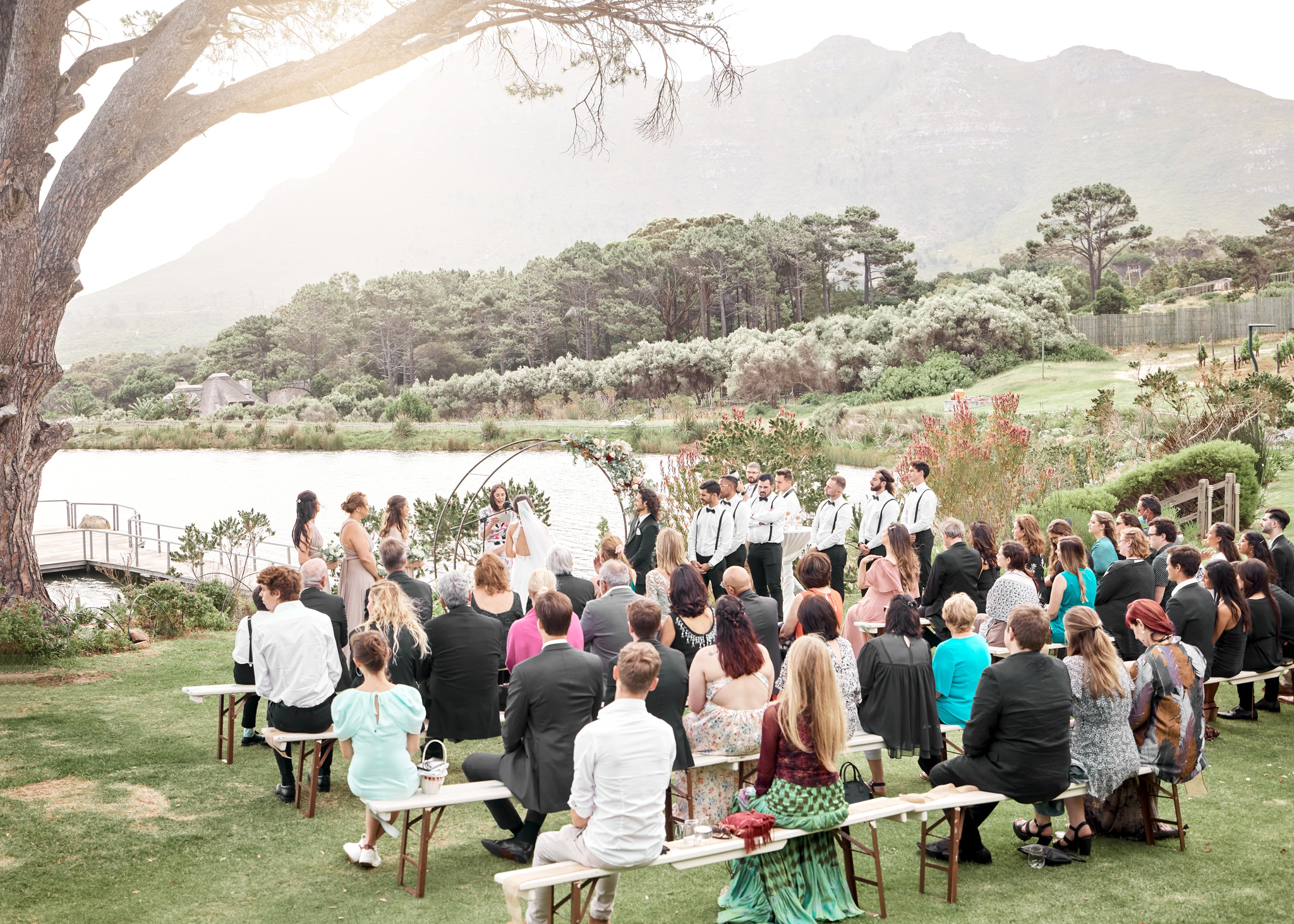 Outdoor wedding ceremony with guests seated and couple at the altar, mountain backdrop