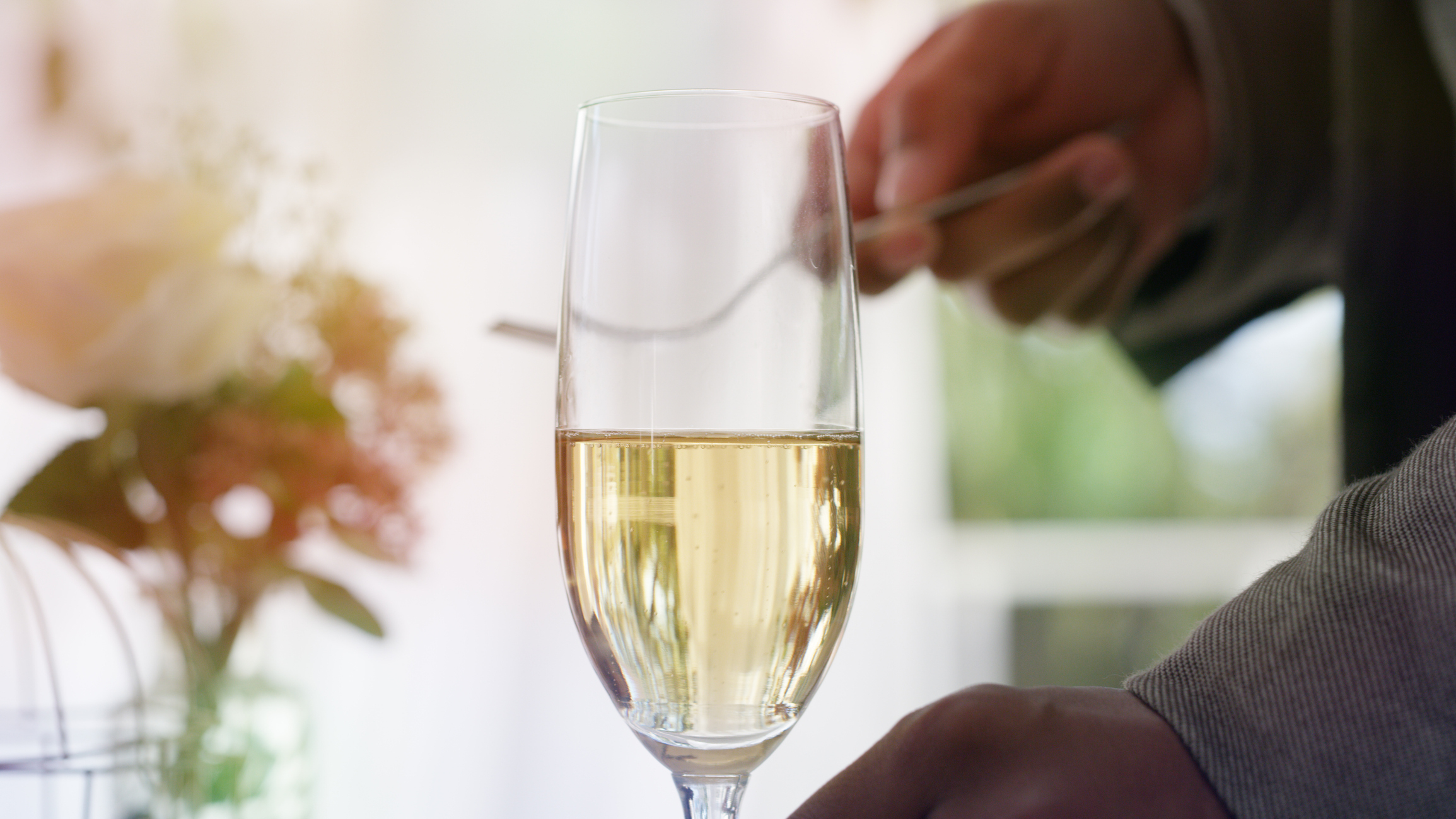 Close-up of a person&#x27;s hand holding a half-full champagne flute