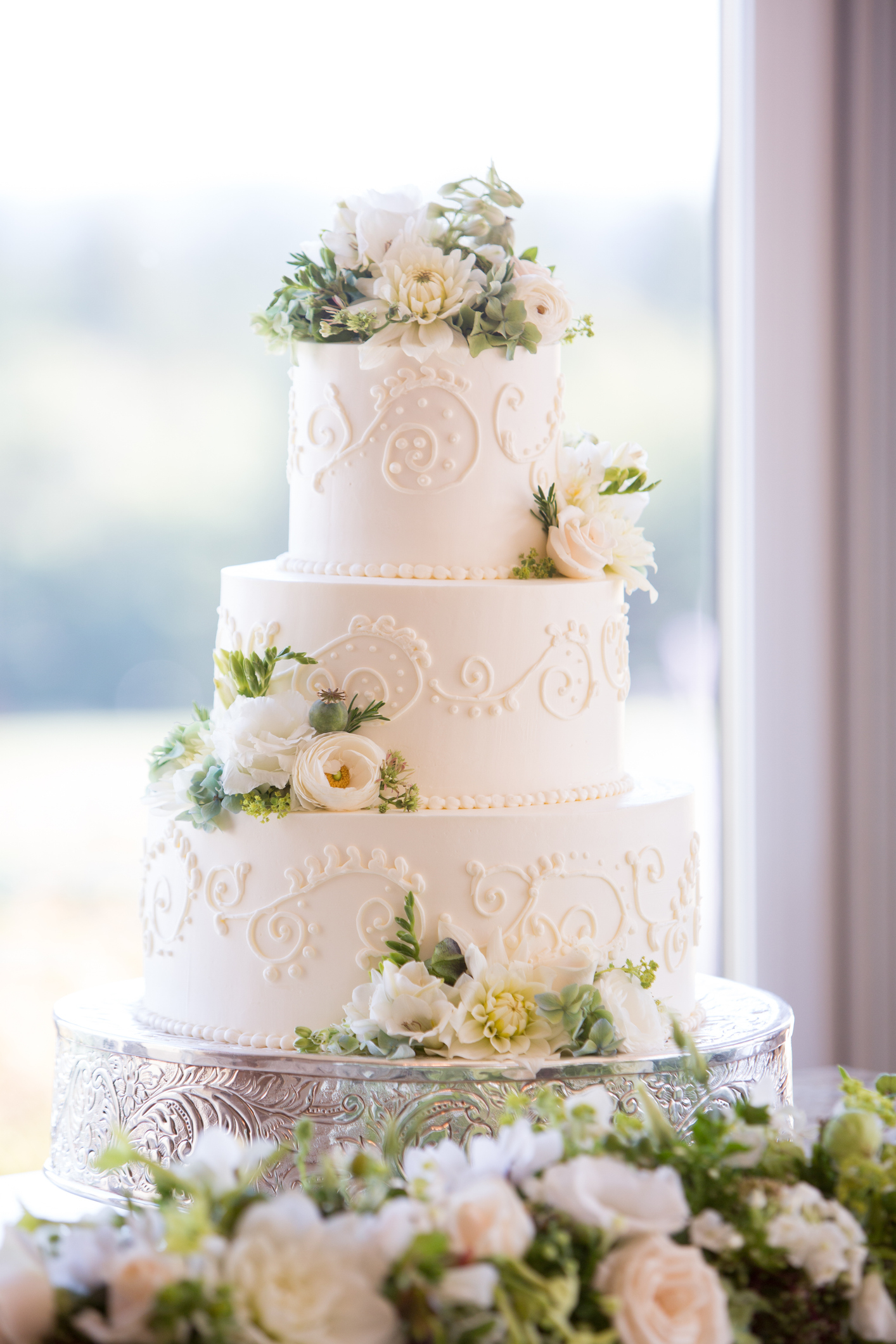 Three-tiered wedding cake with white icing and floral decorations