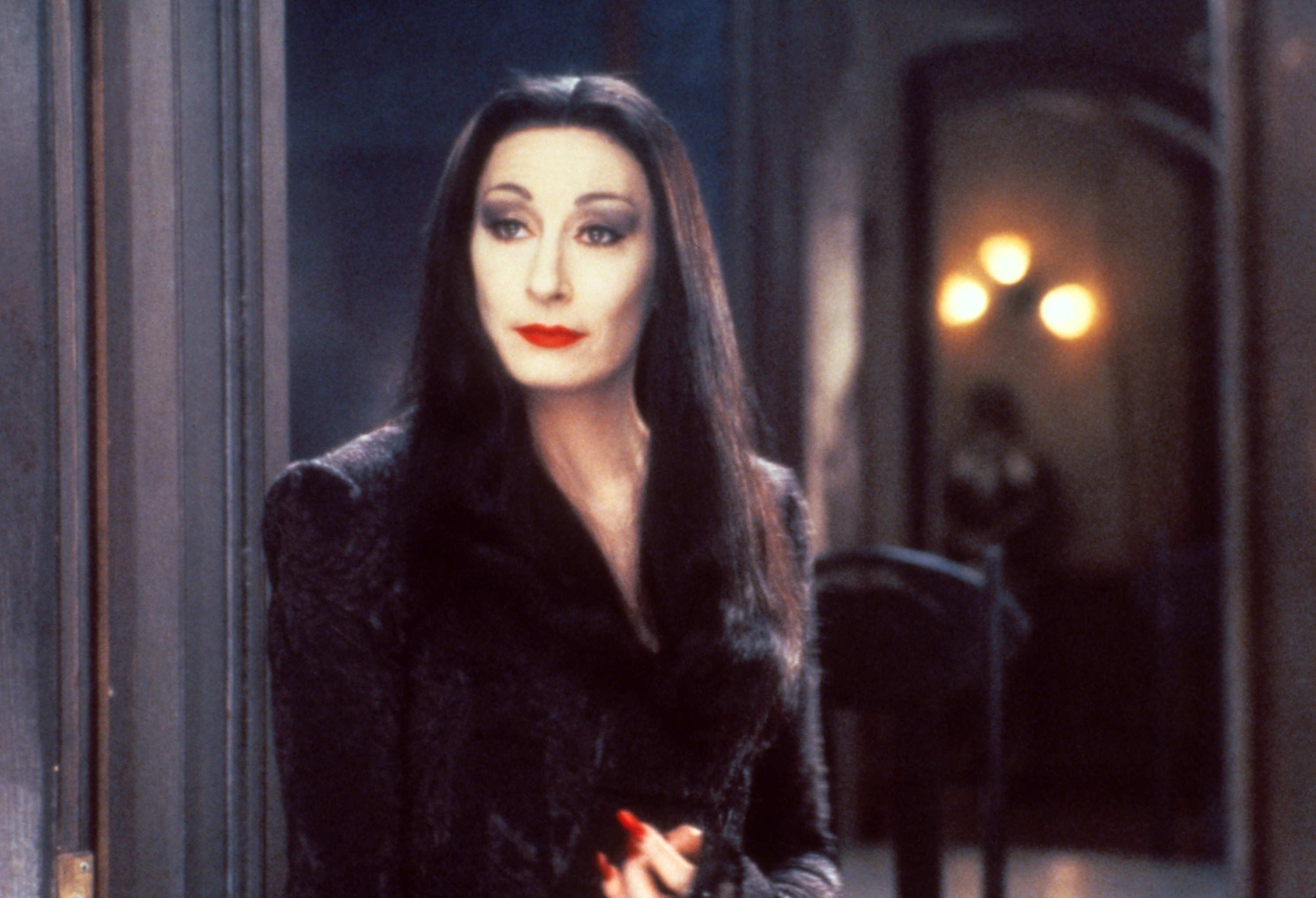 Morticia Addams from &quot;The Addams Family&quot; stands solemnly, dressed in her signature long black dress