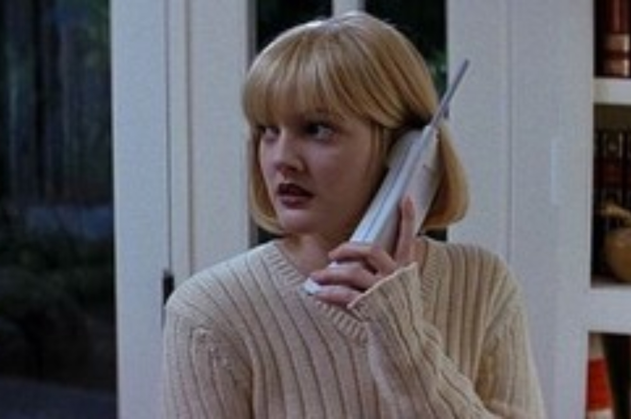 Drew Barrymore as Casey Becker in &quot;Scream,&quot; holding a cordless phone, looking worried. She wears a knitted sweater
