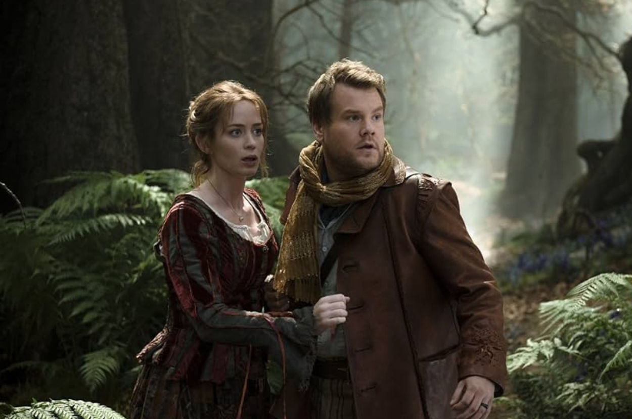 Two characters from the film &quot;Into the Woods&quot; looking alarmed in a forest. Woman in a decorative dress, man in a jacket and scarf