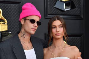 Justin Bieber in a black suit and pink beanie, Hailey Bieber in a strapless white dress, posing together