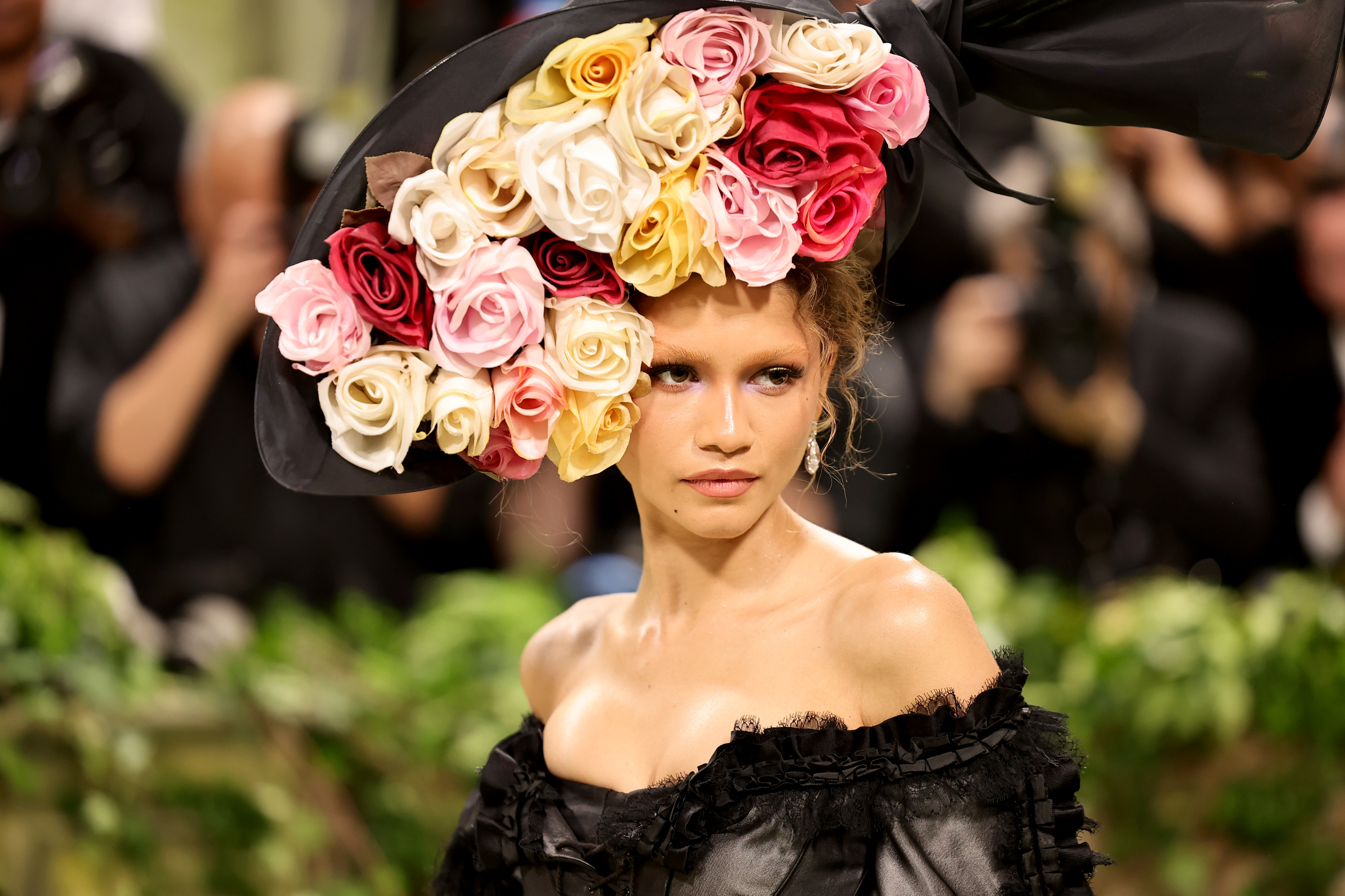 Model on the runway wearing an elaborate floral headpiece and a ruffled black off-the-shoulder gown