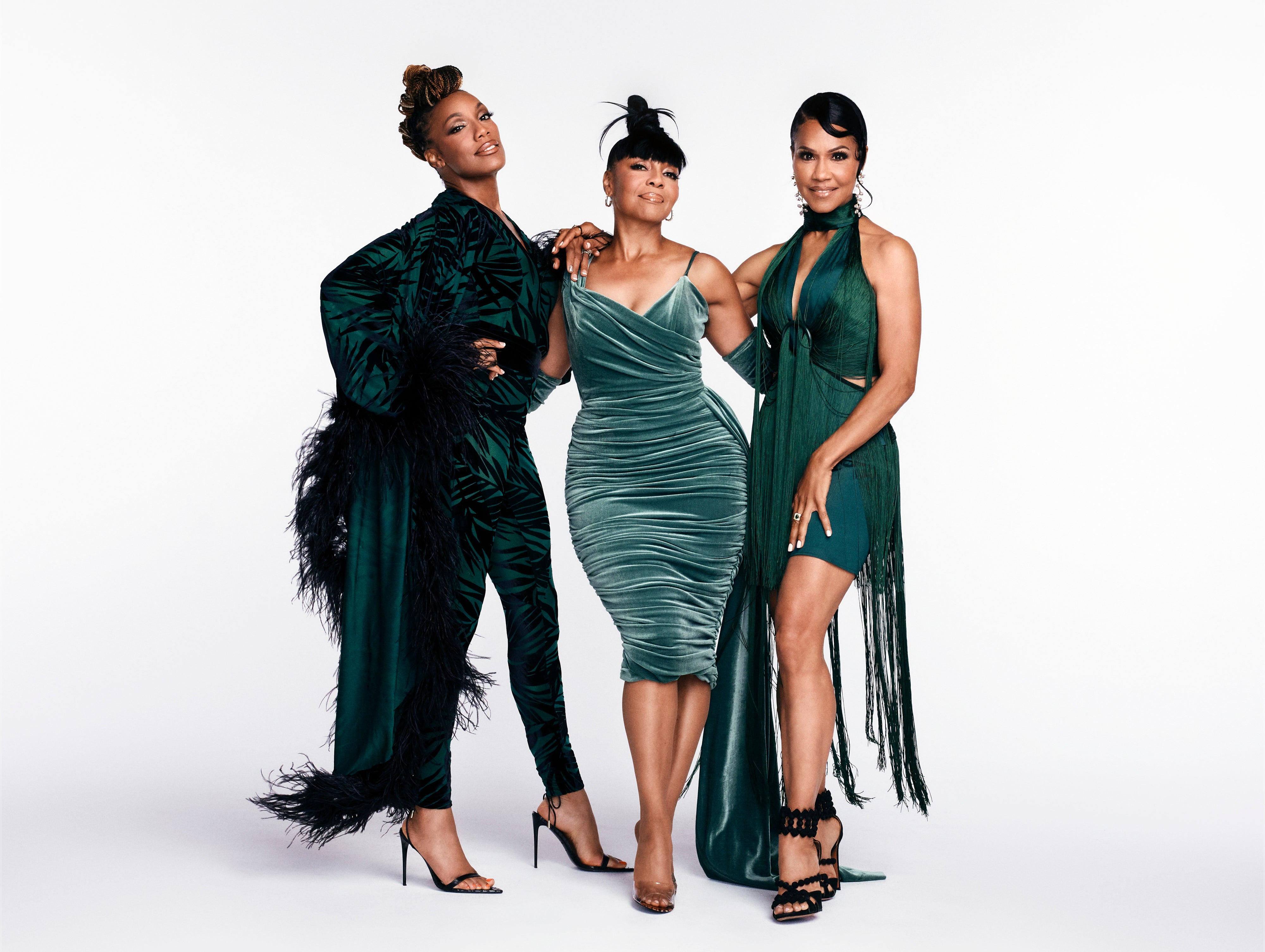 Three women posing in elegant feathered and fringe dresses