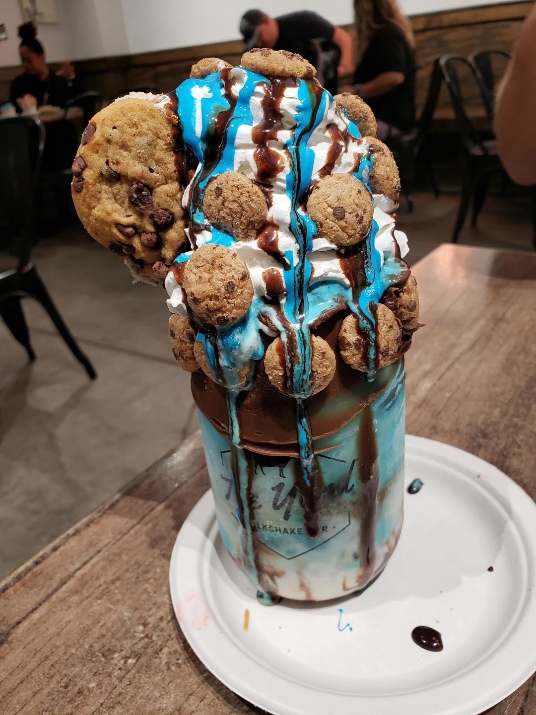 Over-the-top milkshake topped with whipped cream, chocolate syrup, cookie chunks, and a large cookie