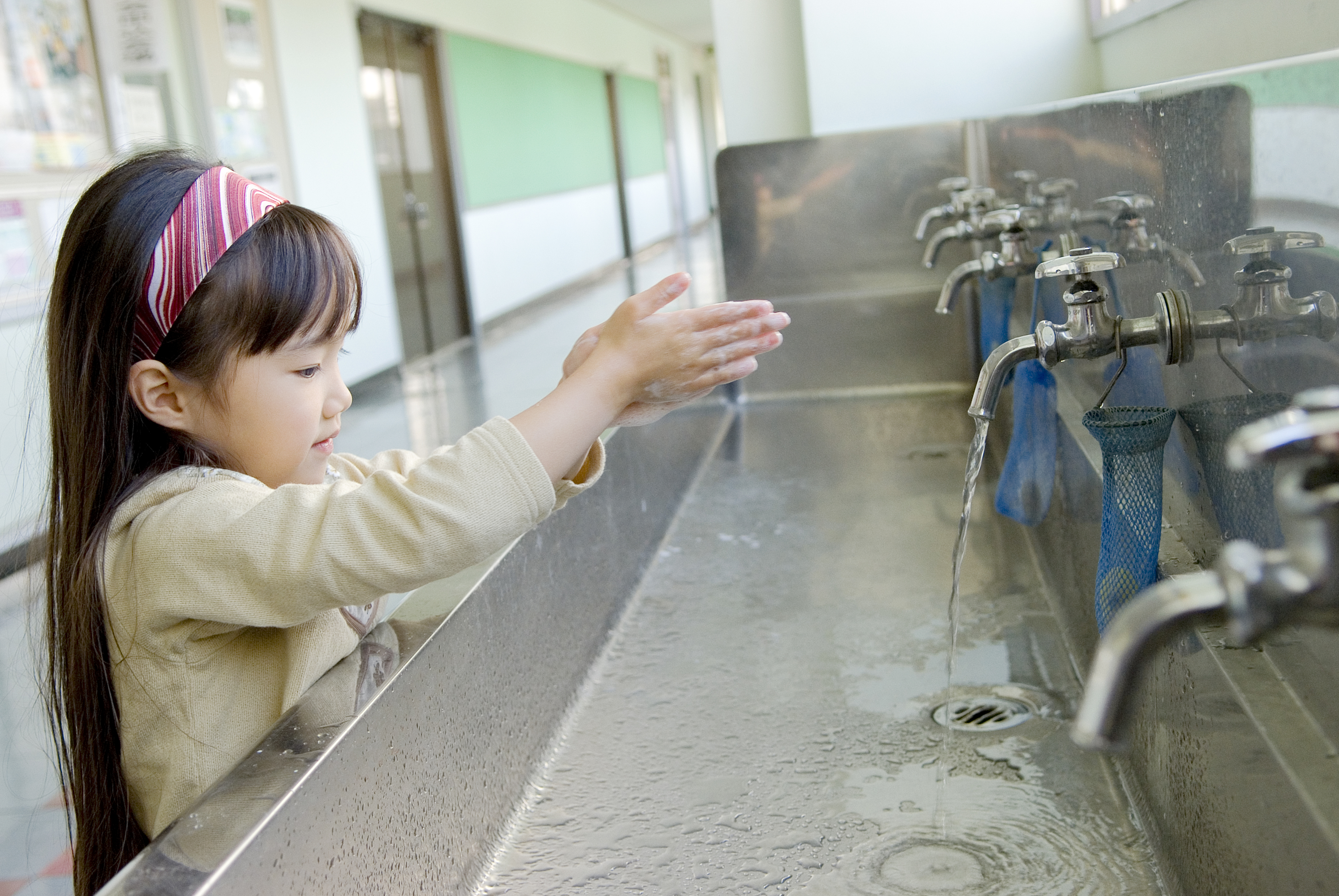A young child washes hands at a public sink, highlighting hygienic practices while traveling