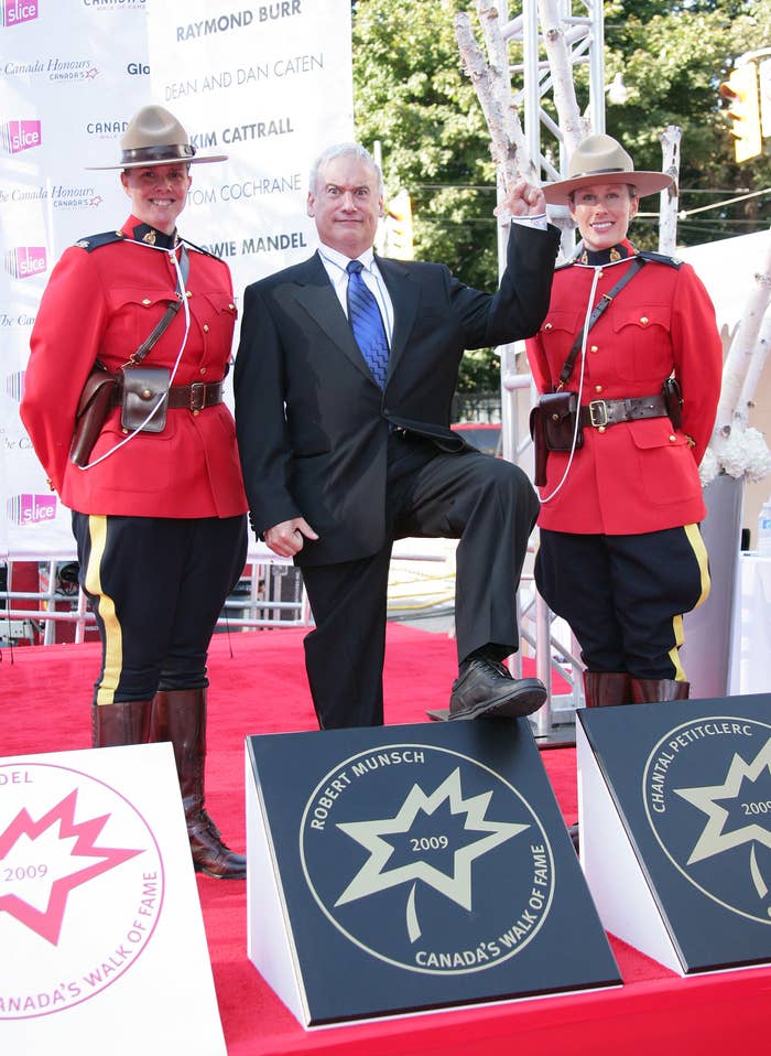 Individual in a suit flanked by two people in red ceremonial uniforms on a walk of fame