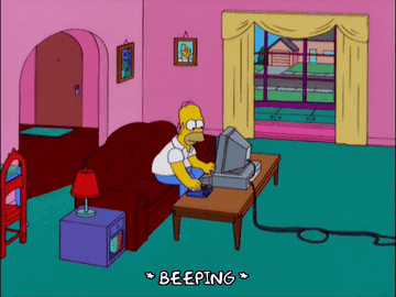 Homer Simpson sitting at a computer, frustratedly typing in a cartoon living room