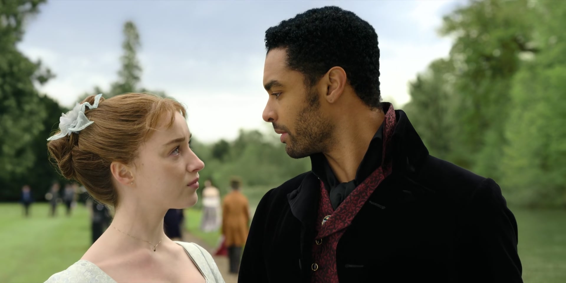 Woman and man in period clothing gaze at each other with a park scene behind them