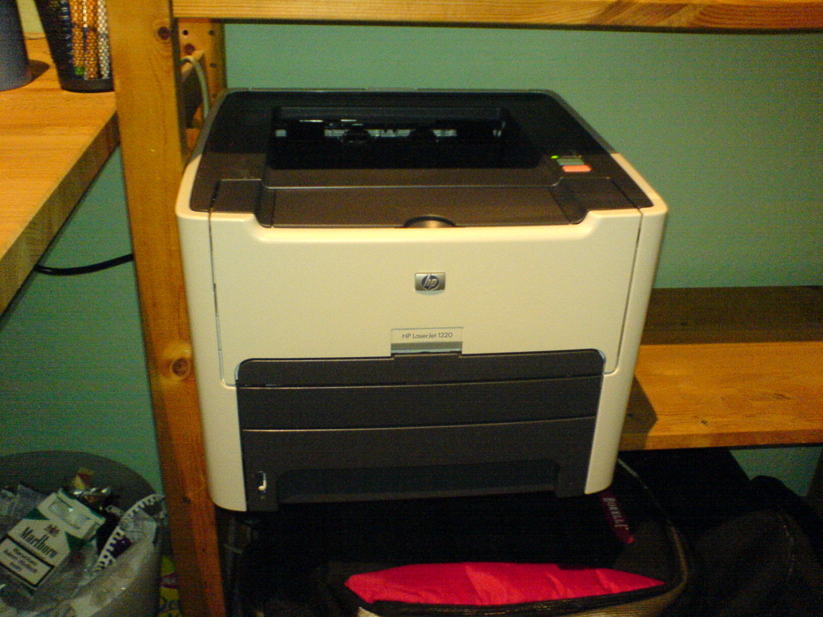 HP LaserJet printer on a wooden desk next to shelves