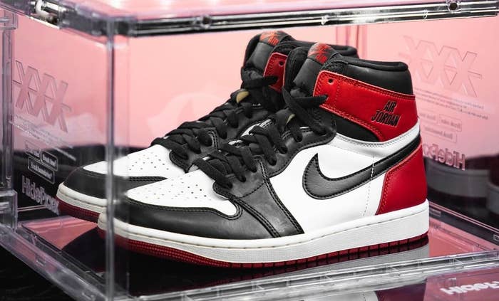 A pair of Air Jordan 1 sneakers displayed in a transparent case on a table
