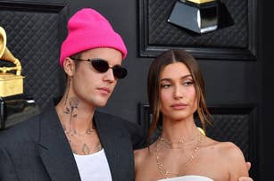 Justin Bieber in a black suit and pink beanie, Hailey Bieber in a strapless white dress, posing together