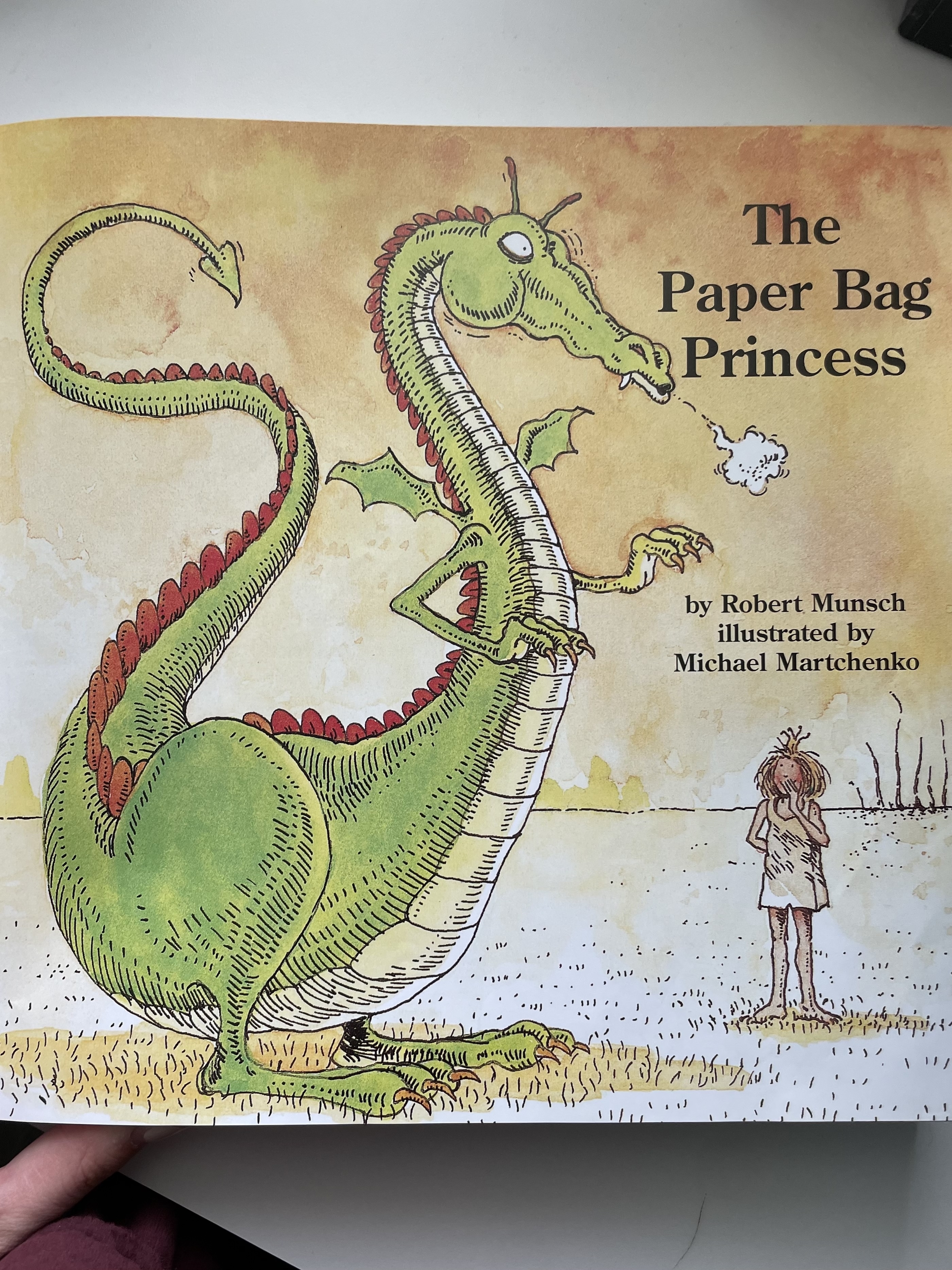 Illustration of a green dragon and a small girl from the book &quot;The Paper Bag Princess&quot; by Robert Munsch