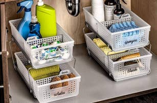 Assorted cleaning supplies organized in labeled white bins under a sink