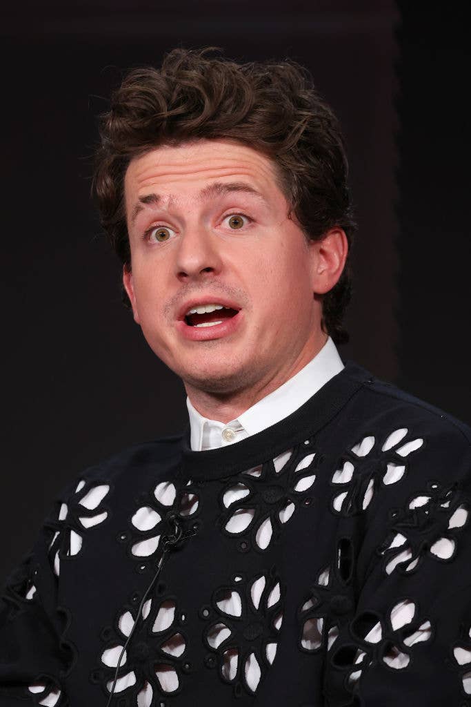 Charlie with expressive face, wearing a unique patterned top, speaking at an event