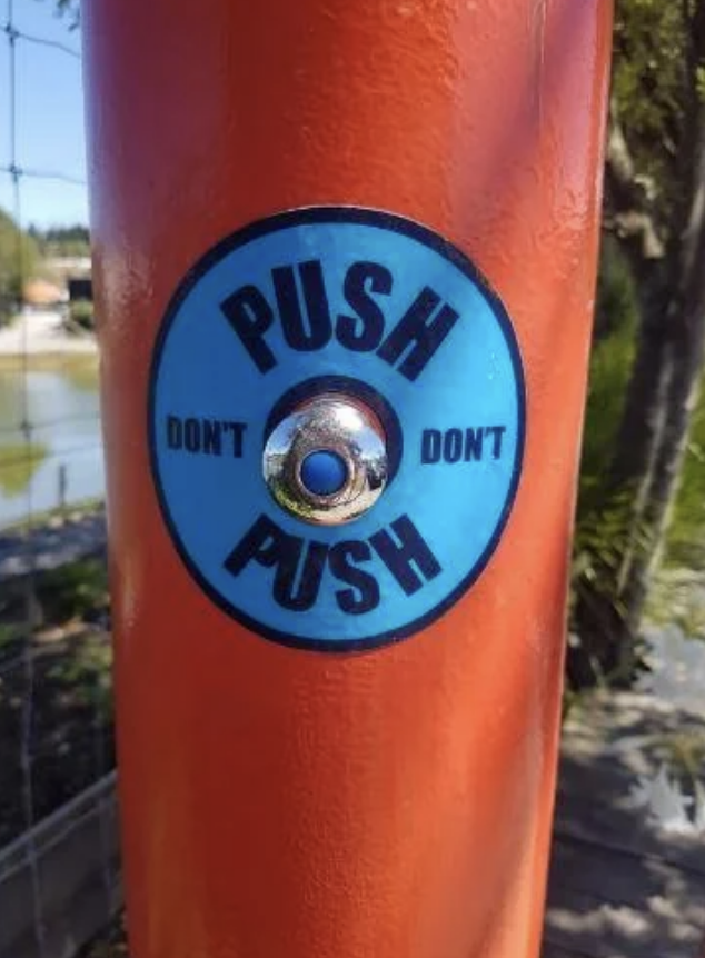 Circular button on a pole with contradictory instructions &quot;PUSH DON&#x27;T PUSH.&quot;