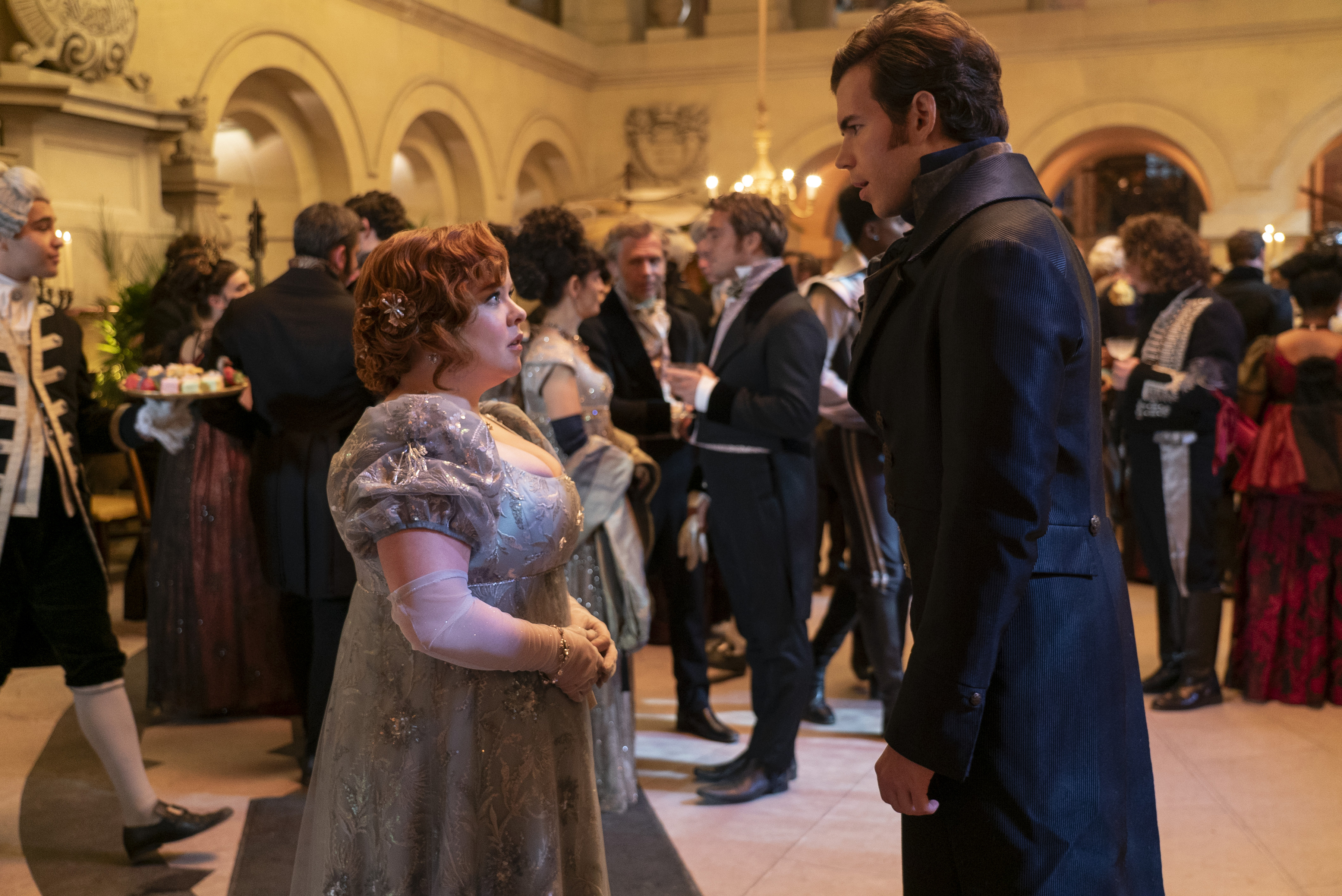 Penelope Featherington and Colin Bridgerton in period attire at a ball in a scene from Bridgerton