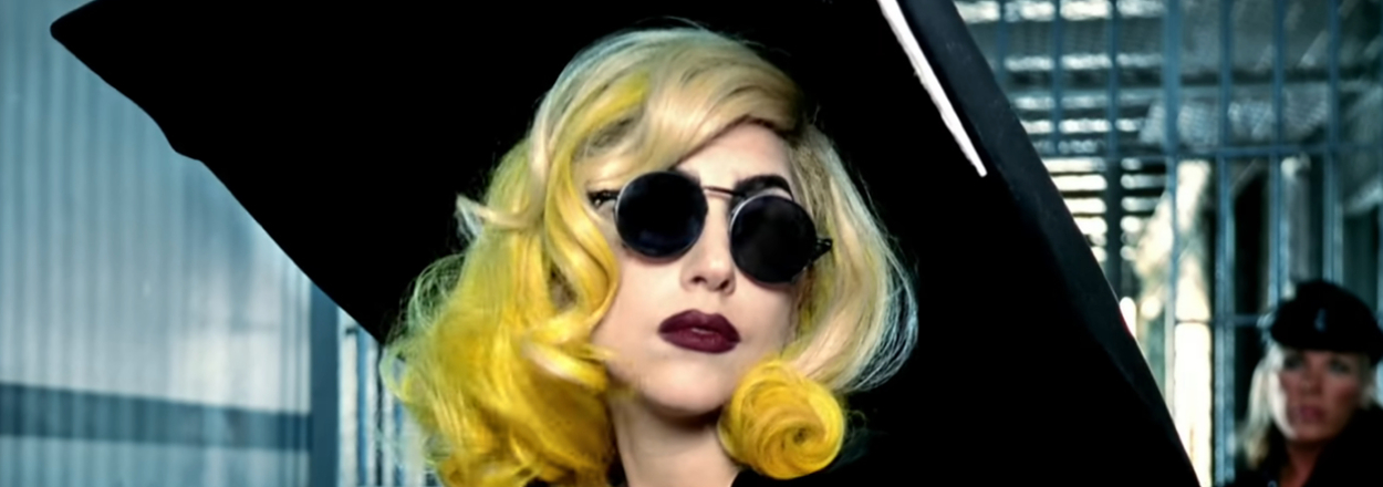 Lady Gaga wearing a large hat, elegant clothing, and round sunglasses while rocking dyed hair in the telephone music video