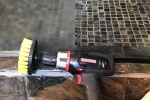 Cordless Craftsman power brush being used for cleaning near a fireplace, with focus on the tool's functionality for home maintenance