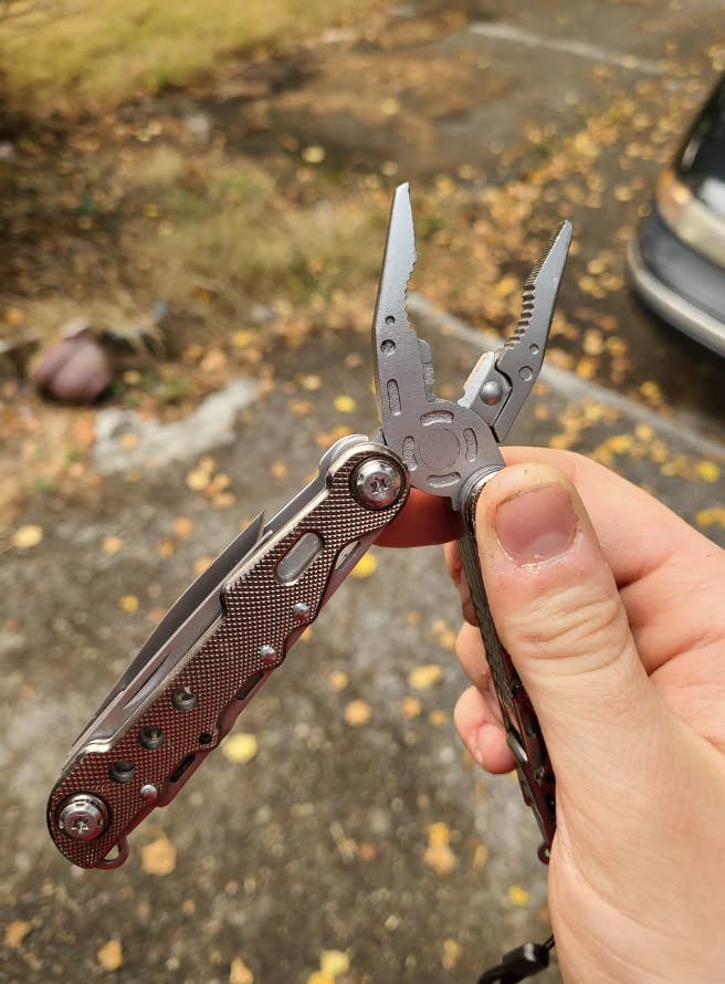 Person&#x27;s hand holding a multi-tool with pliers extended