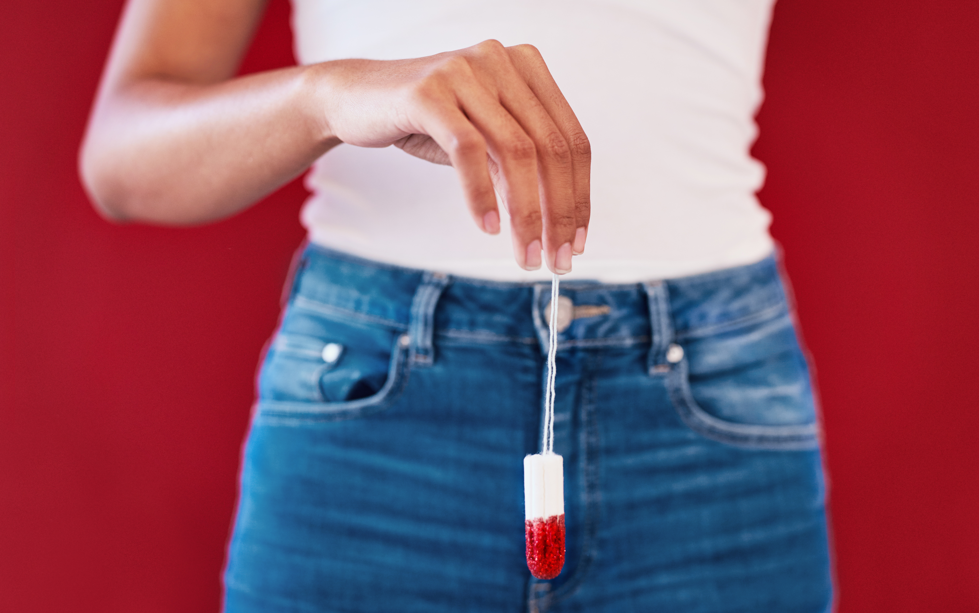 Woman holding a tampon that&#x27;s been dipped in red liquid