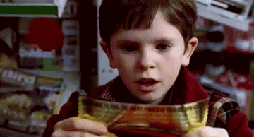 Charlie holding up a golden ticket