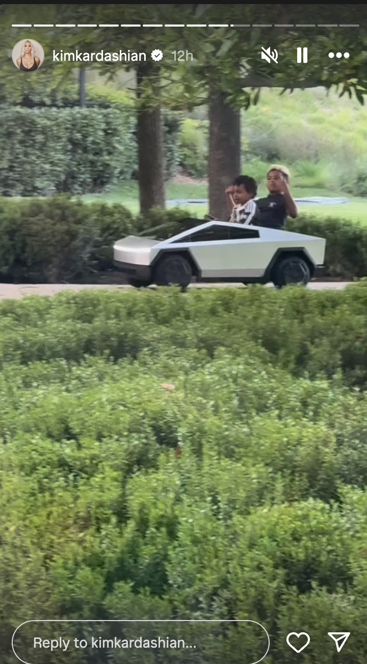 Kim Kardashian and a child in a small, futuristic car-shaped toy vehicle outdoors