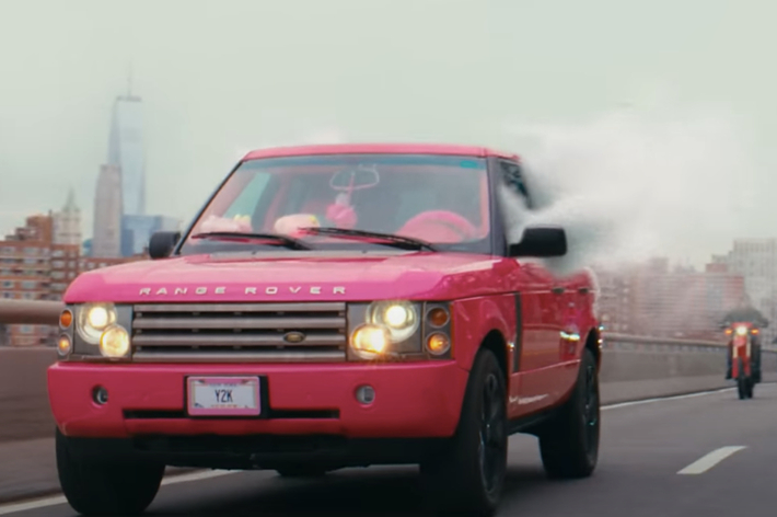 Range Rover driving on a bridge with smoke coming from its hood, followed by motorcyclists